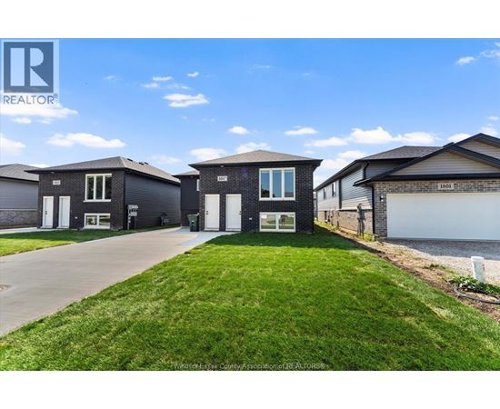 A realtor photo of a house with a well-maintained lawn and a clear sky.