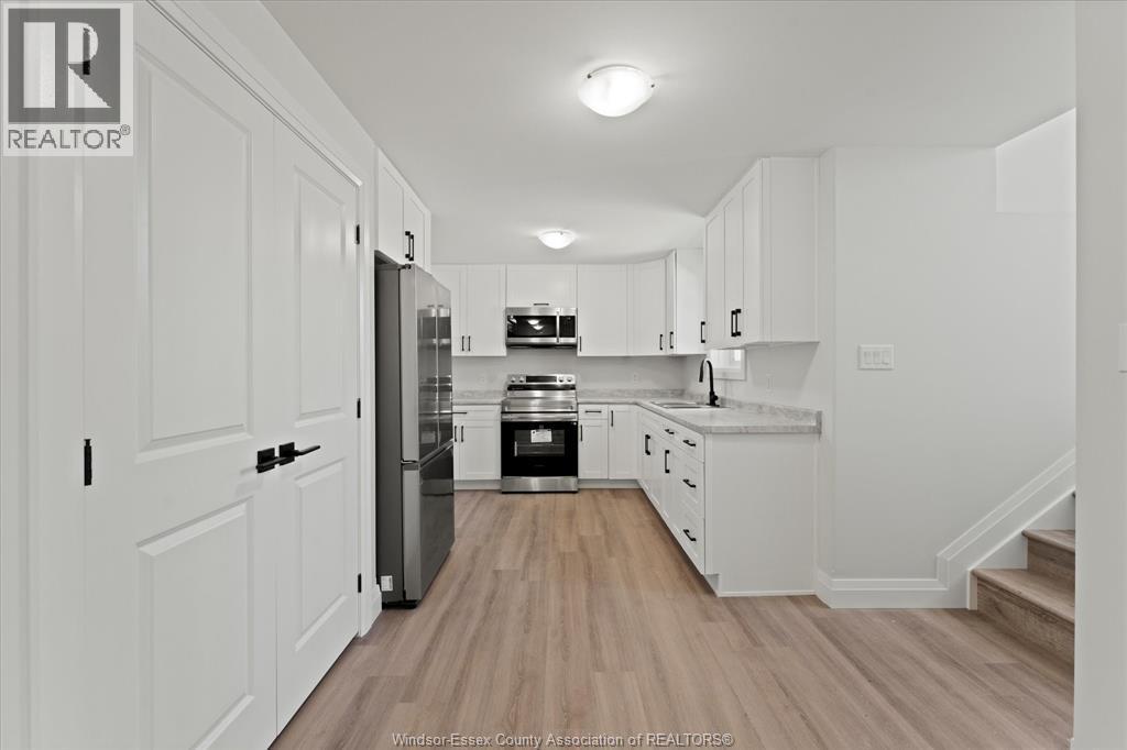 A kitchen with white cabinets and a wooden floor.