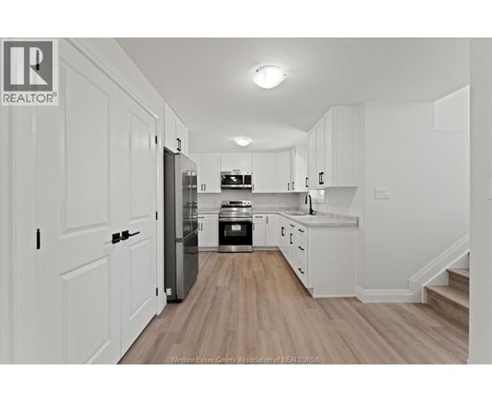 A kitchen with white cabinets and a wooden floor.