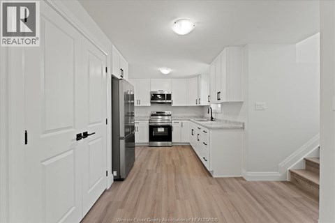 A kitchen with white cabinets and a wooden floor.