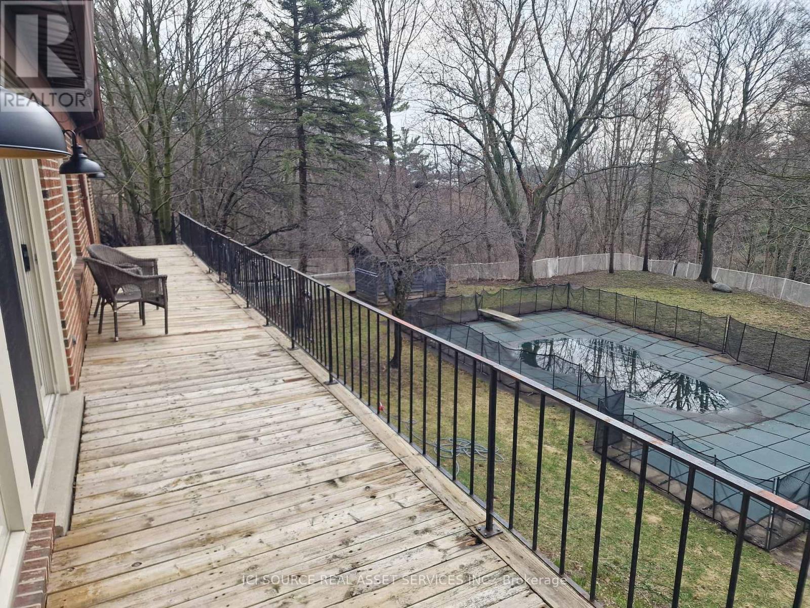 A deck with a railing and a pool in the backyard.