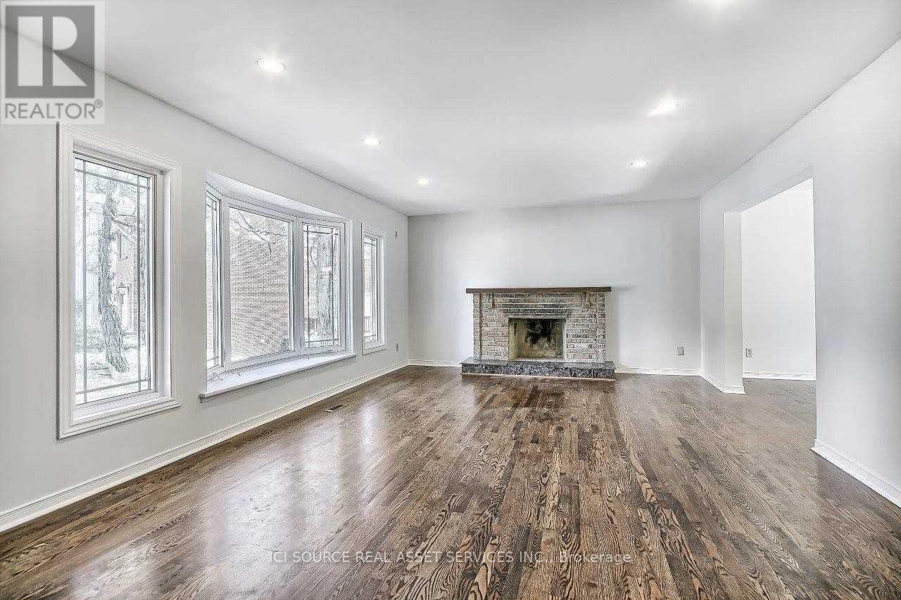A spacious room with a fireplace and wood flooring.