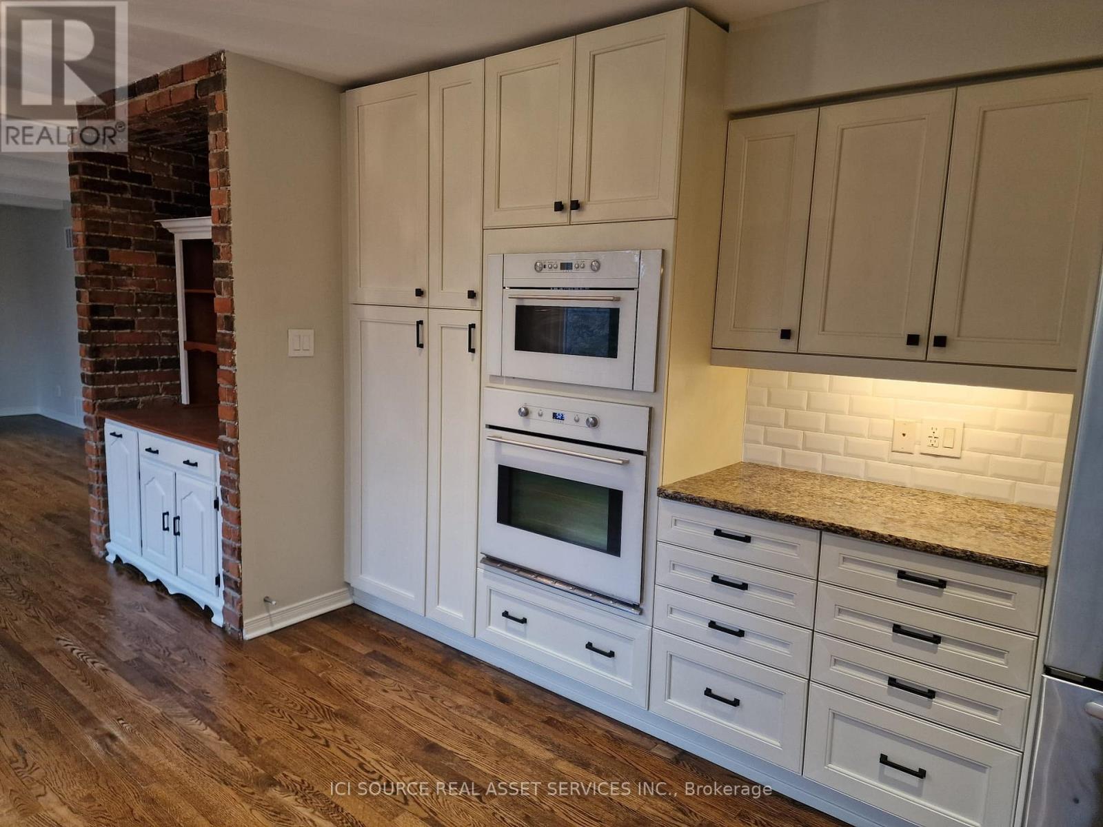 A kitchen with white cabinets and a brick wall.