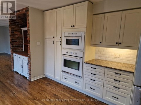 A kitchen with white cabinets and a brick wall.
