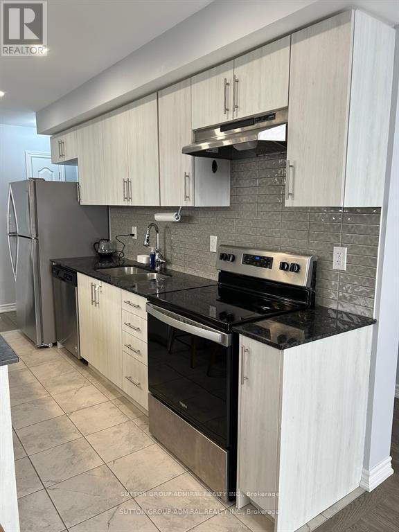A kitchen with white cabinets and black countertops.