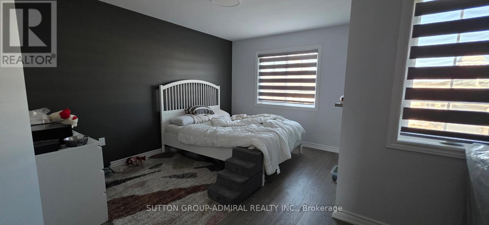 A bedroom with a bed, dresser, and window with blinds.