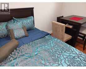 A bed with blue bedding and a brown headboard is in the image.