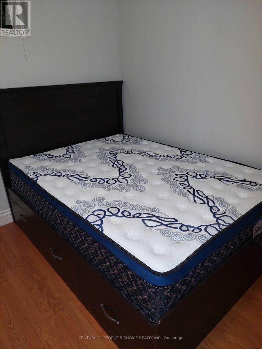 A mattress with a blue and white pattern is on a wooden floor.