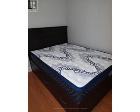 A mattress with a blue and white pattern is on a wooden floor.