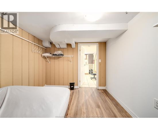 A bedroom with a bed on the left and a hallway on the right.