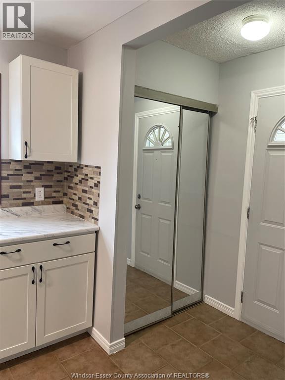 A bathroom with a tiled wall and a glass door.
