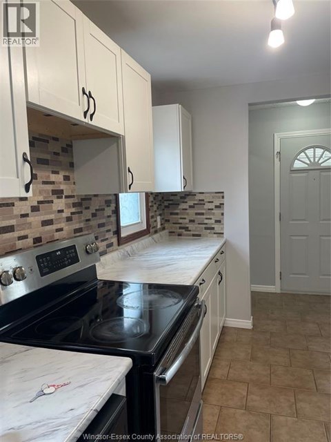 A kitchen with white cabinets and a black stove top.