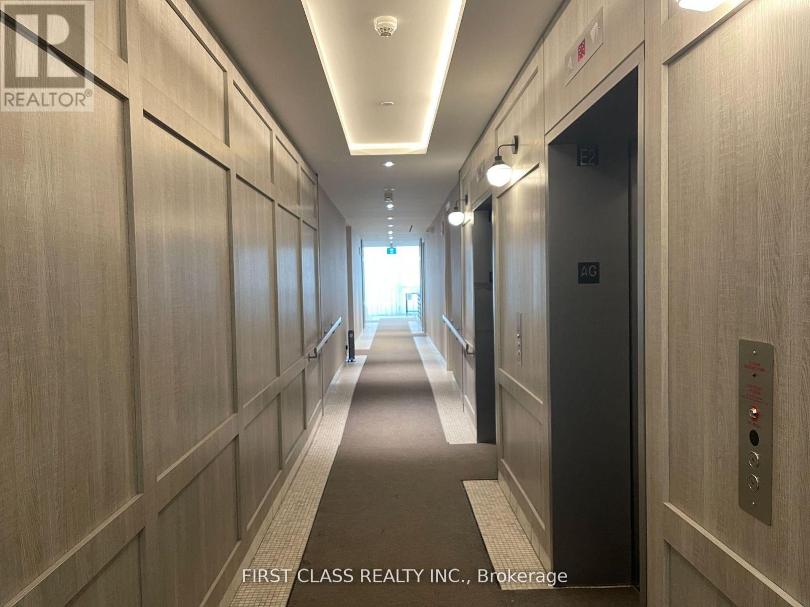 A hallway with a First Class Realty Inc. sign on the wall.