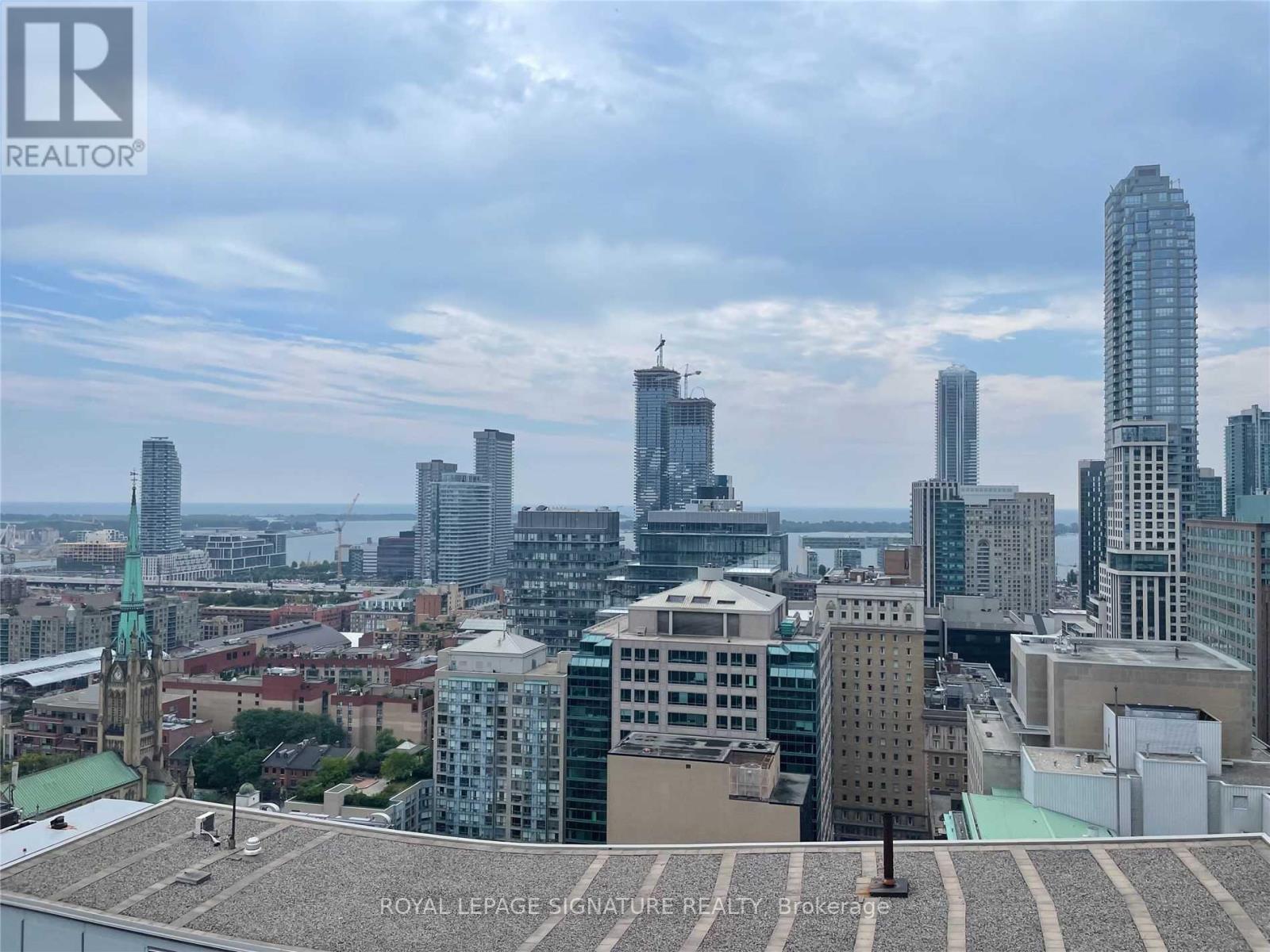A cityscape with a mix of modern and older buildings, with a cloudy sky above.
