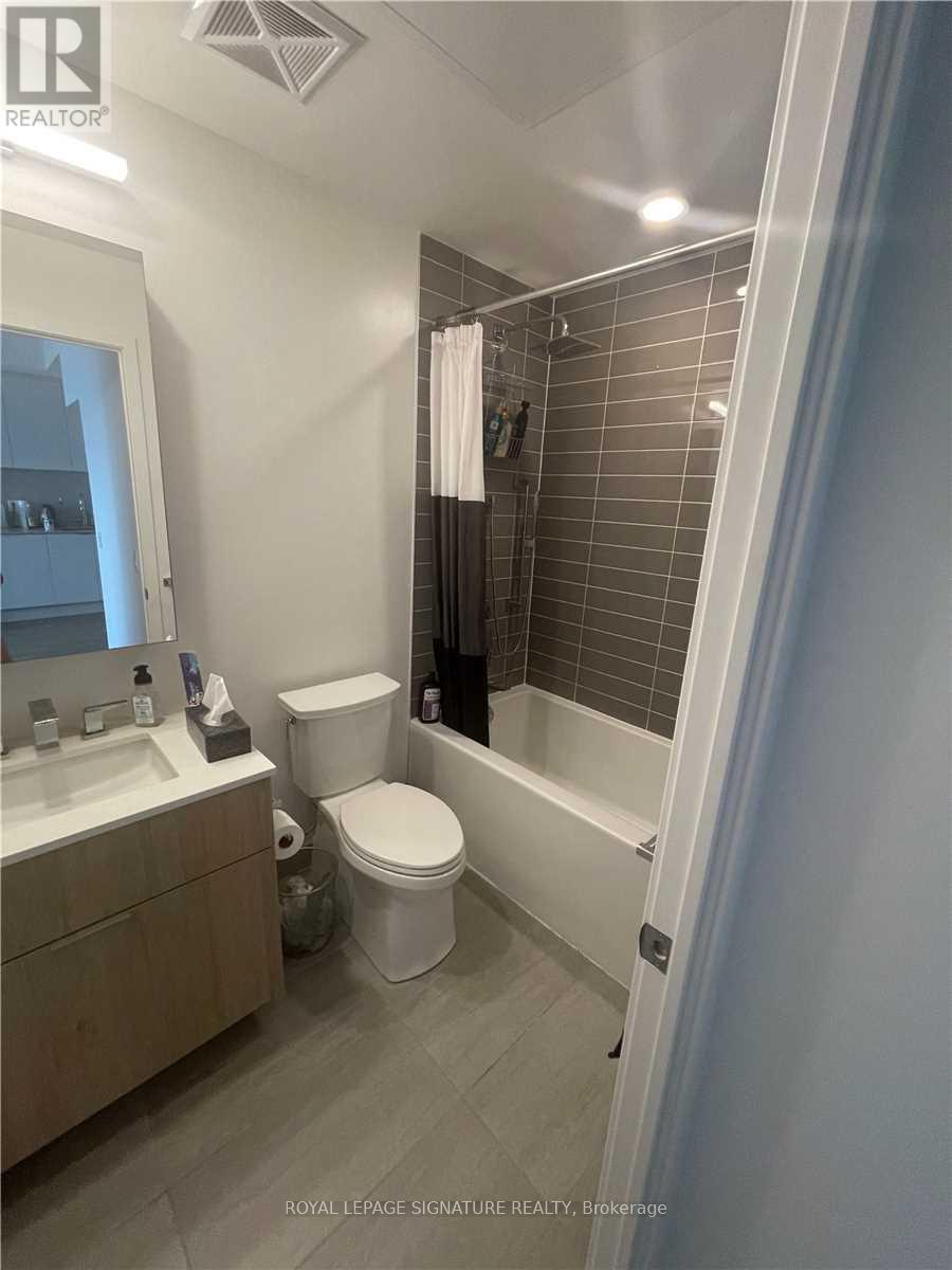A white toilet sits in a bathroom next to a sink and a bathtub.