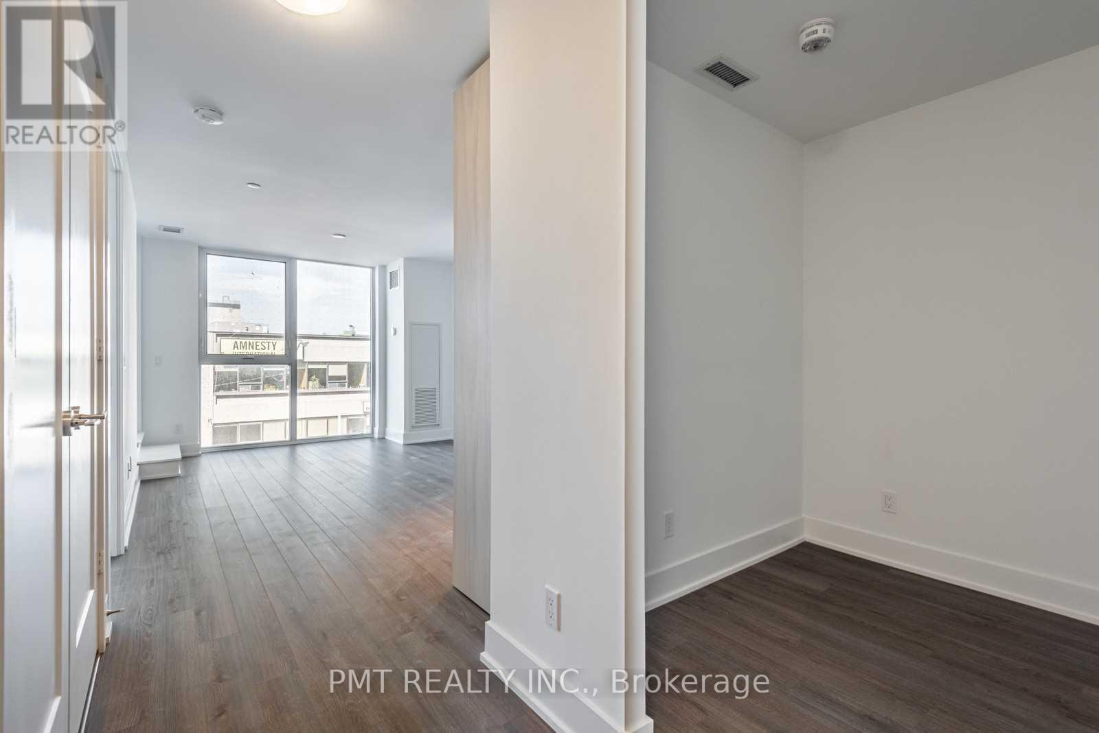 A well-lit, spacious room with wood flooring and white walls.