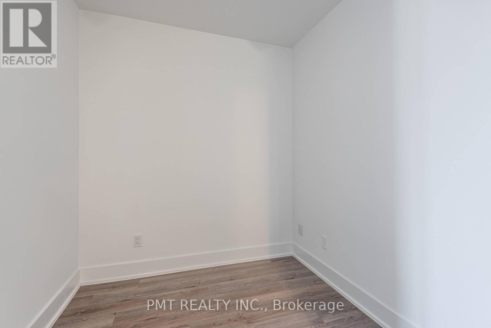 A white room with a wooden floor and a wall socket.