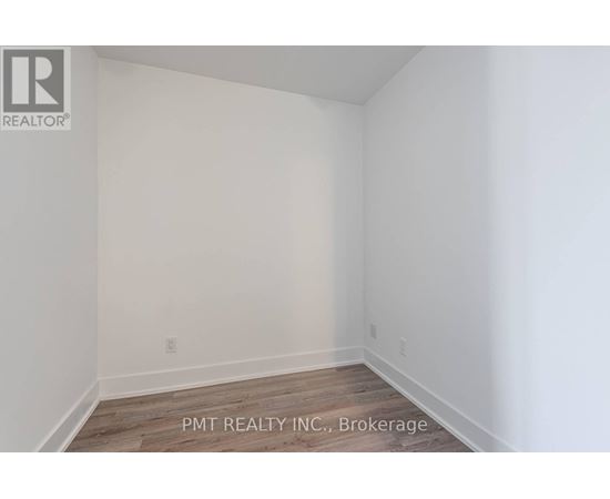 A white room with a wooden floor and a wall socket.