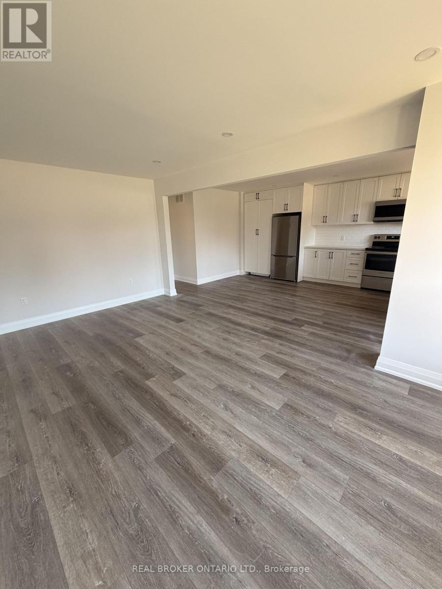 A spacious room with wood flooring and white walls.