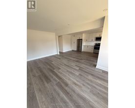A spacious room with wood flooring and white walls.