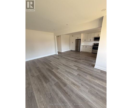 A spacious room with wood flooring and white walls.