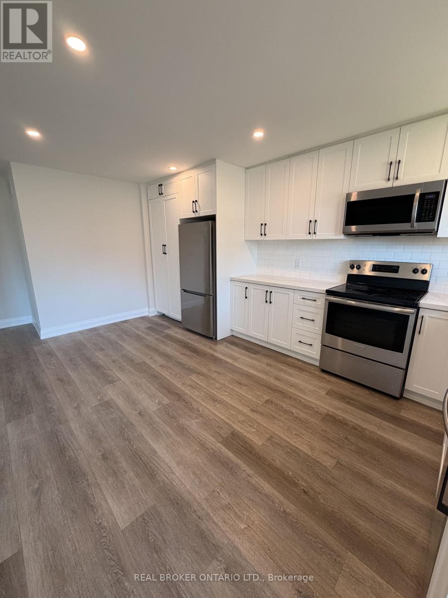 A kitchen with white cabinets and a wooden floor.