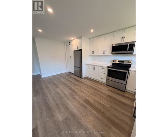 A kitchen with white cabinets and a wooden floor.