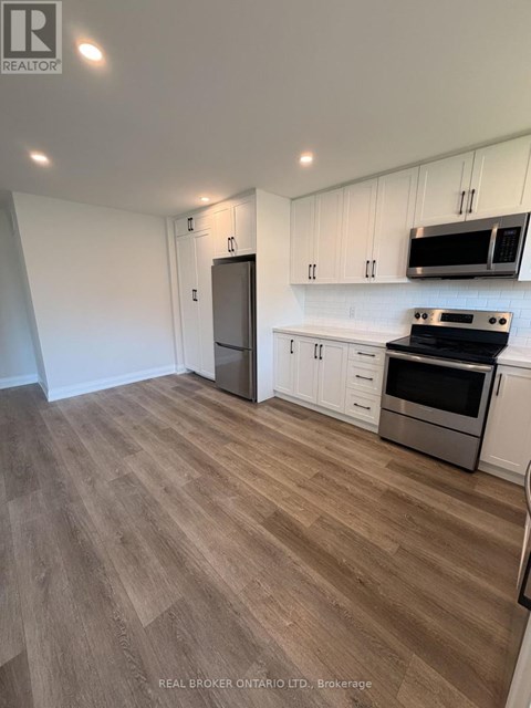 A kitchen with white cabinets and a wooden floor.