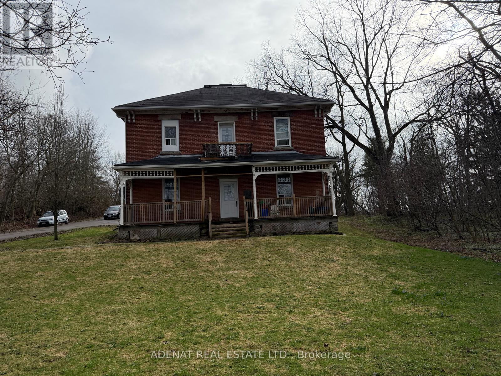 A two-story brick house with a porch and a balcony.
