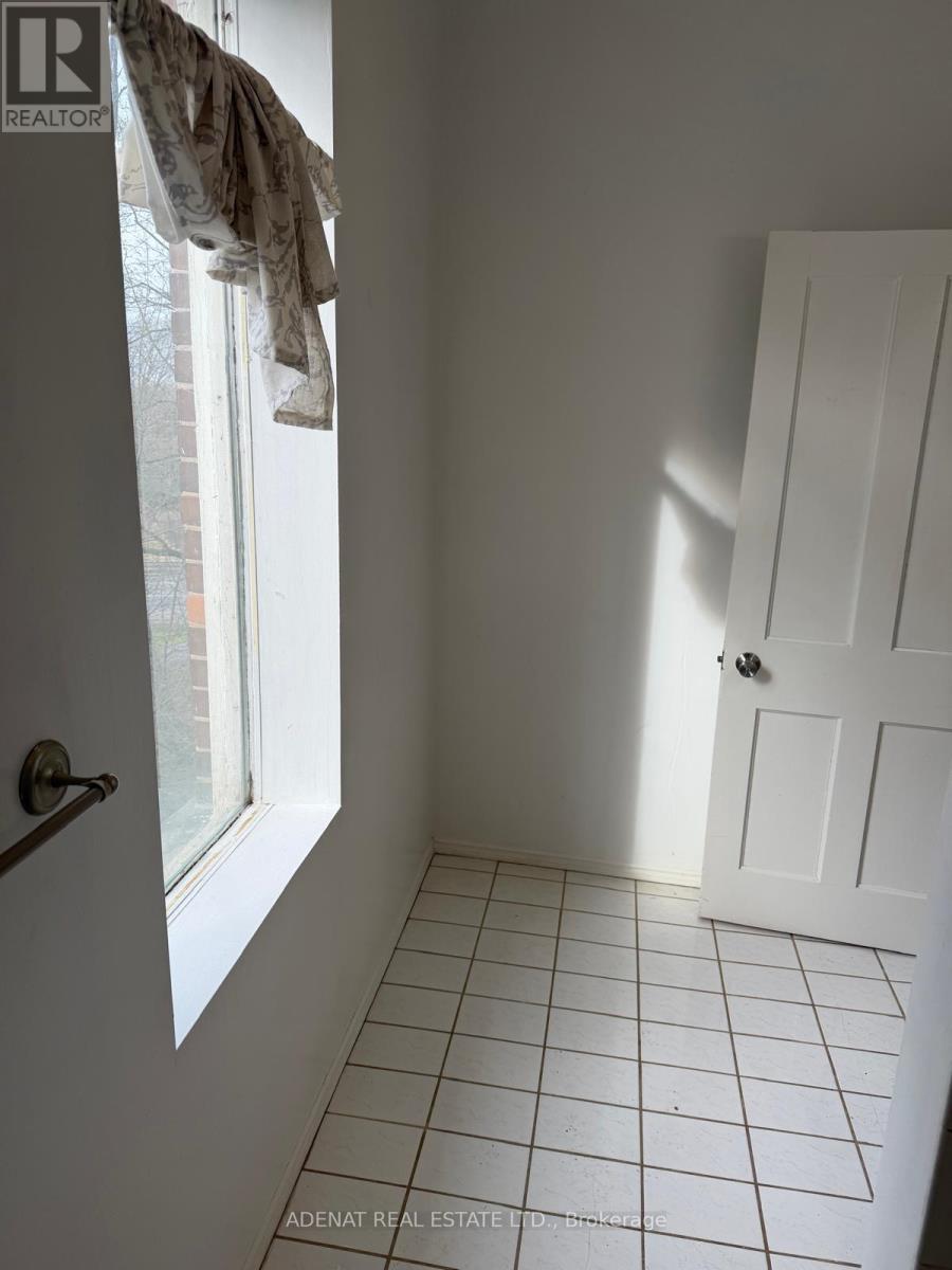A white tiled bathroom with a white door and a window.
