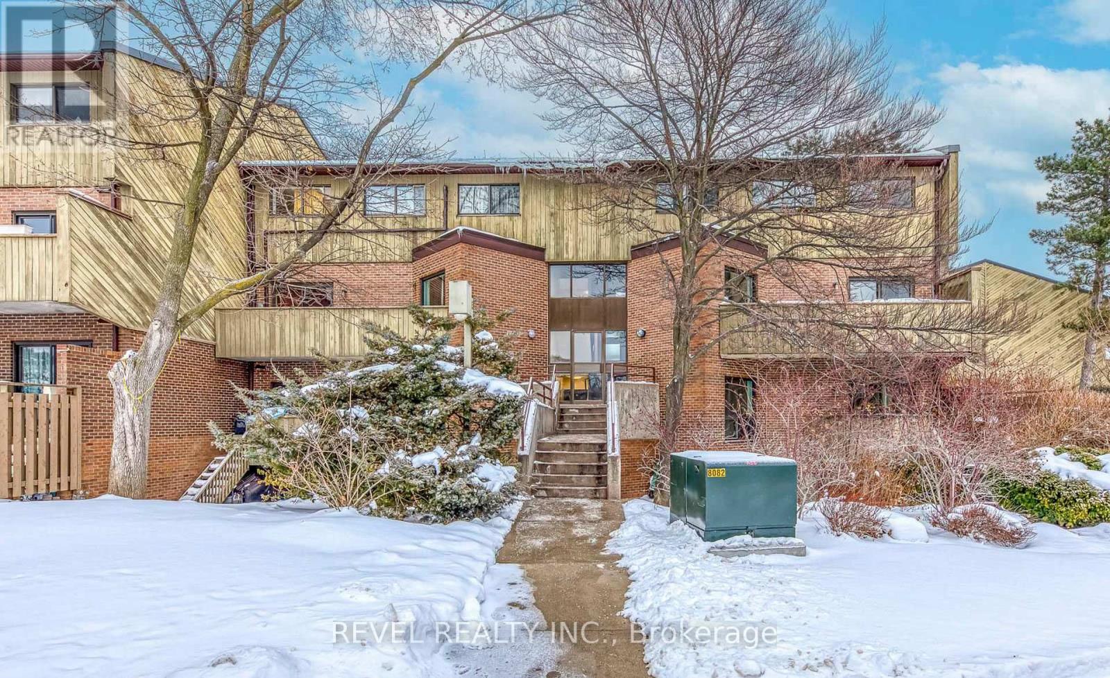 A snow-covered front yard of a multi-story apartment building.