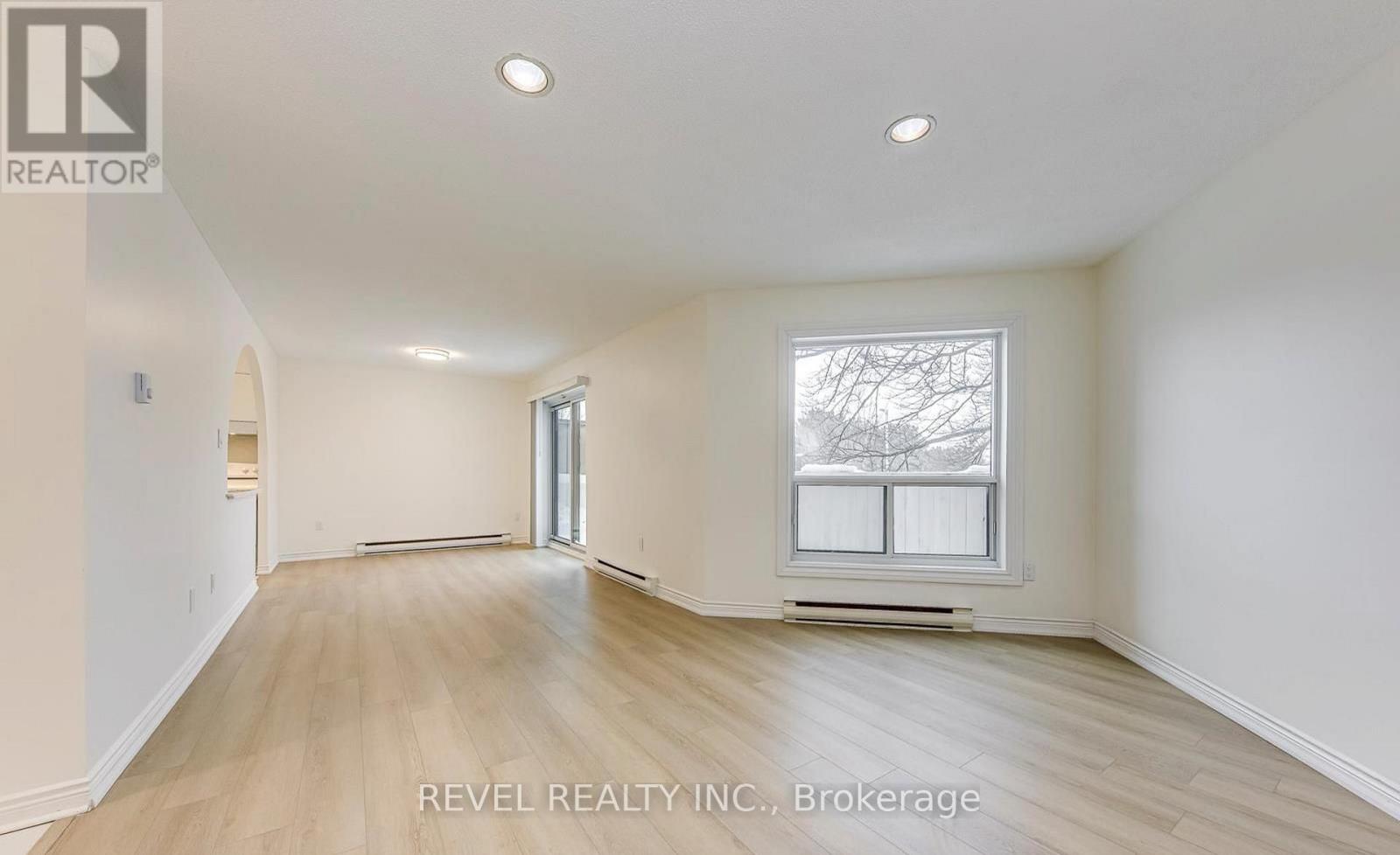 A spacious room with wooden flooring and a large window.