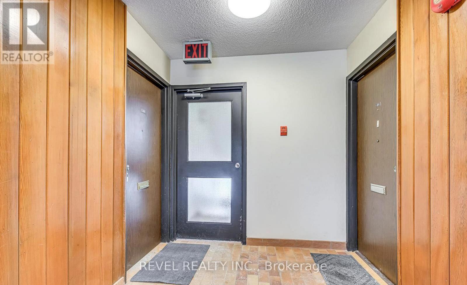 A hallway with a black door and a wooden wall on the left.