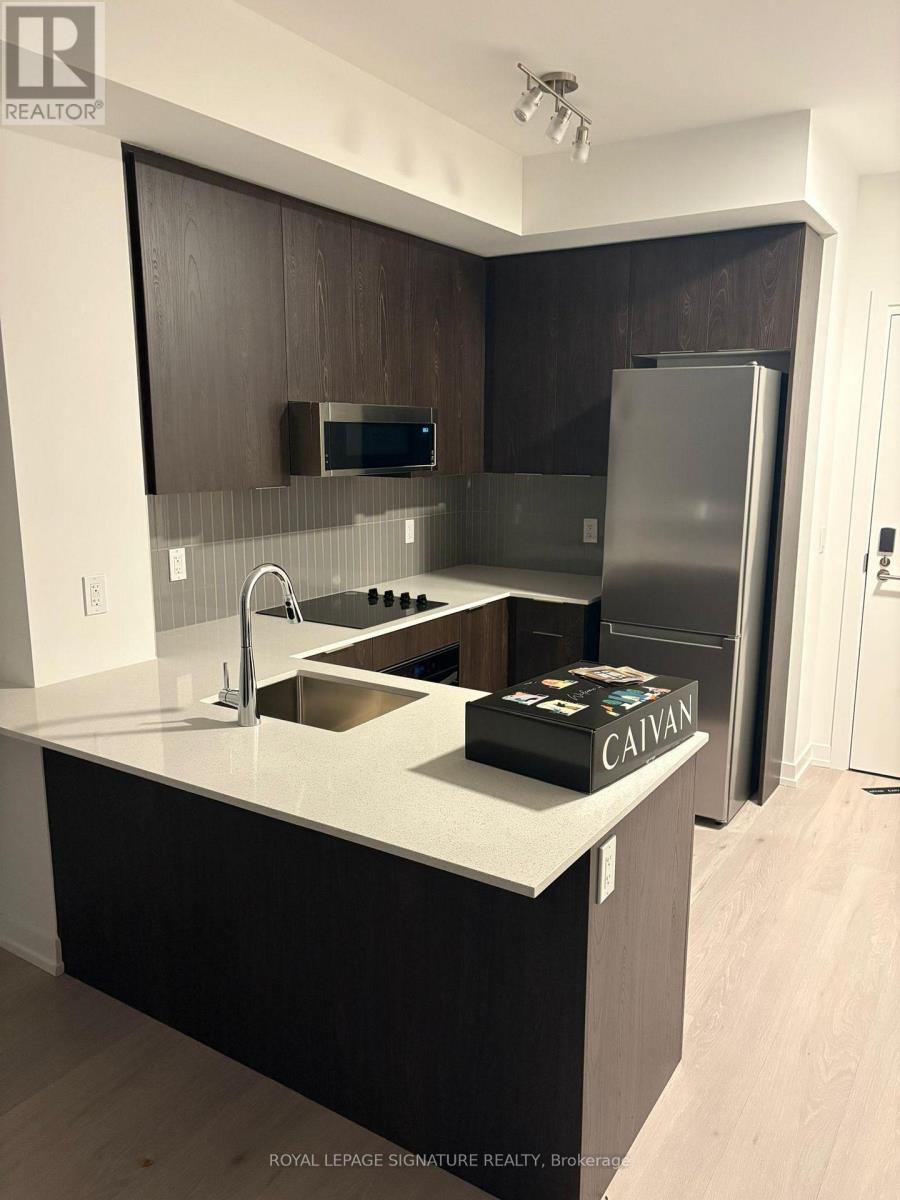 A modern kitchen with dark wood cabinets and stainless steel appliances.