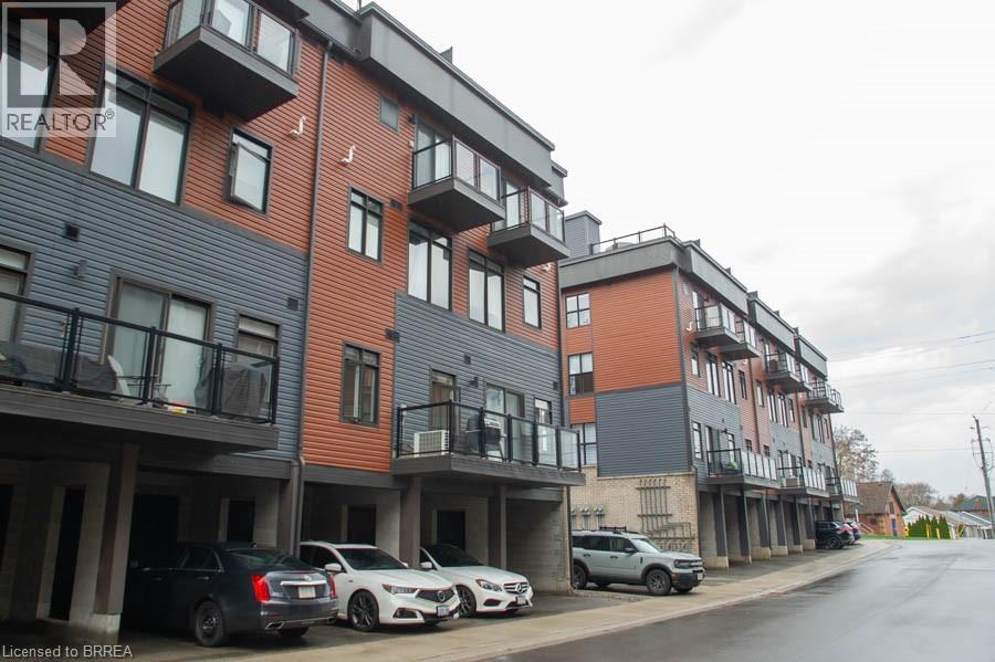 A row of modern apartment buildings with cars parked in front.