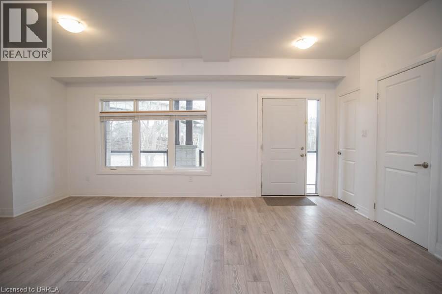A spacious room with wooden flooring and white walls.
