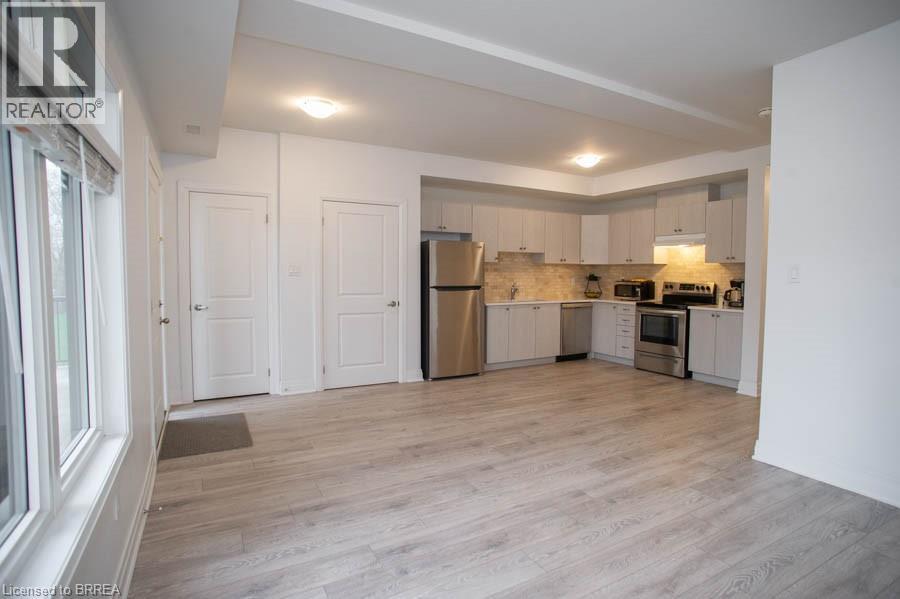 A spacious kitchen with white cabinets and a wooden floor.