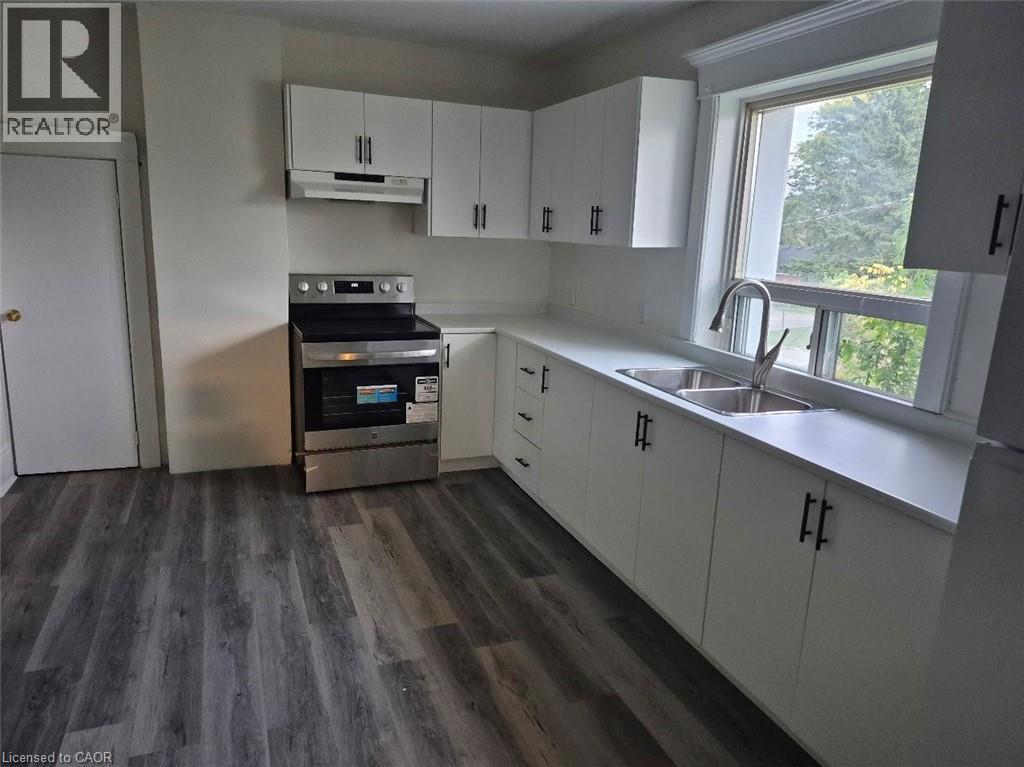 A kitchen with a stove, cabinets, and a window.
