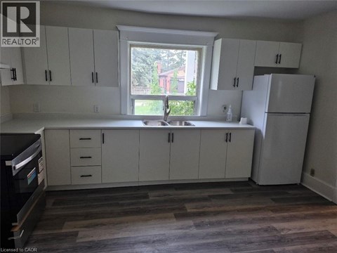 A kitchen with white cabinets and a window.