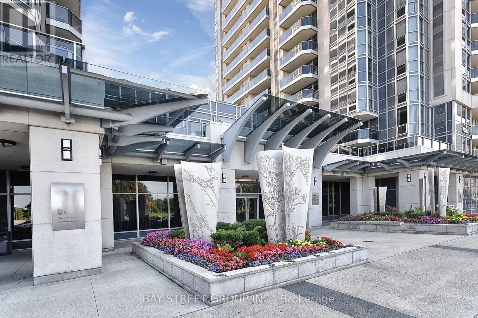 A modern building entrance with a sculpture and flowers.