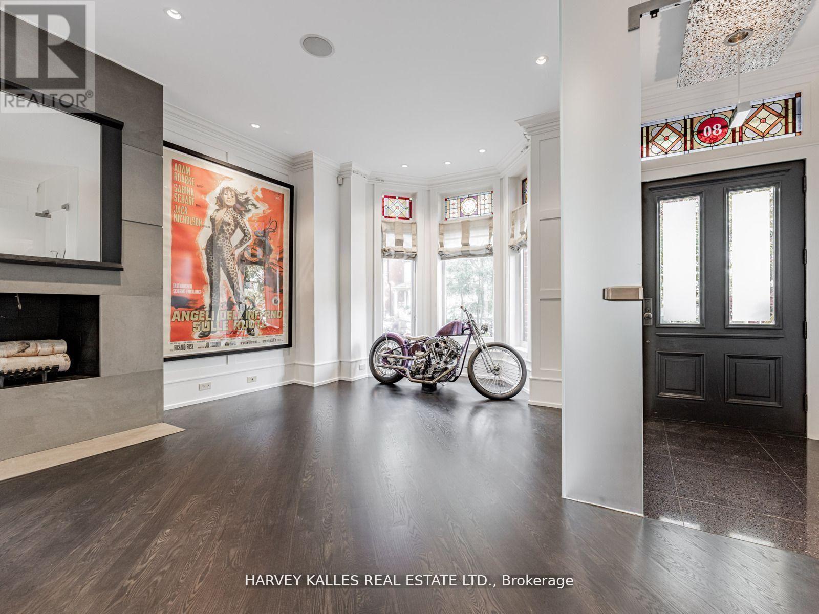 A motorcycle is parked in a spacious room with a fireplace and a large painting on the wall.