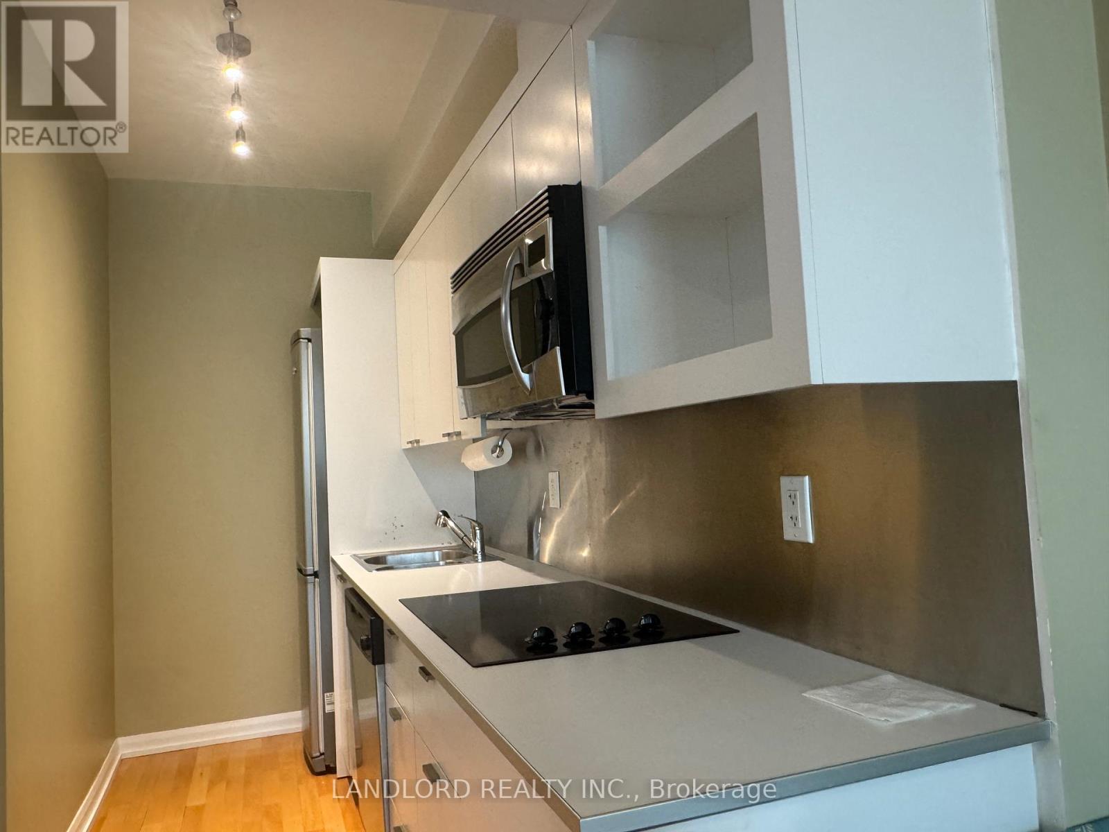 A kitchen with a stainless steel refrigerator and white cabinets.