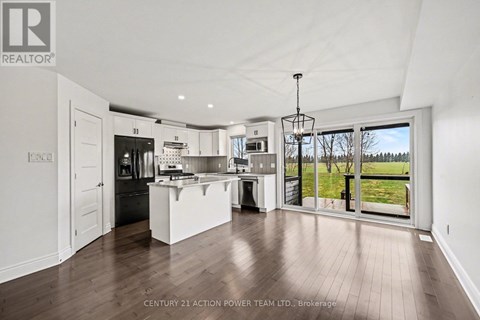 A modern kitchen with white cabinets and a wooden floor.