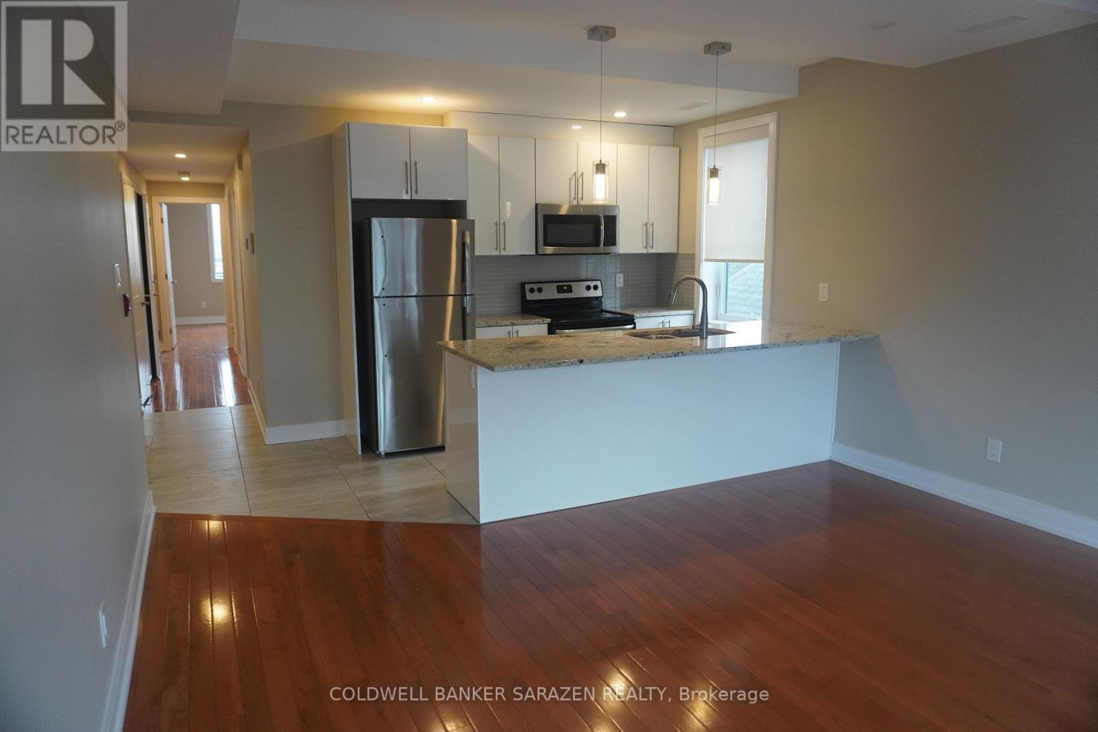 A kitchen with a refrigerator, microwave, and oven.