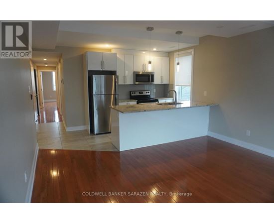 A kitchen with a refrigerator, microwave, and oven.