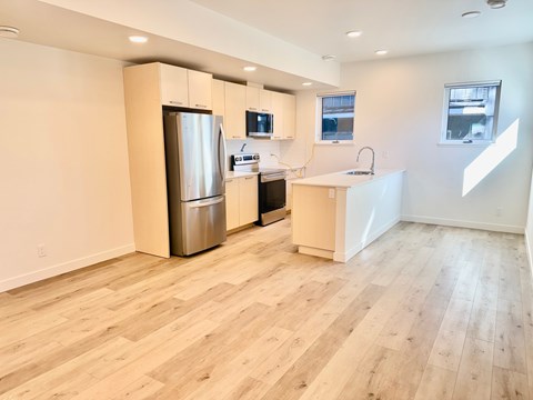 A kitchen with a refrigerator, microwave, and sink.