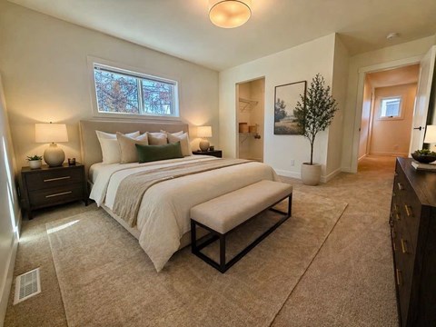 A bedroom with a large bed and a bench in front of it.