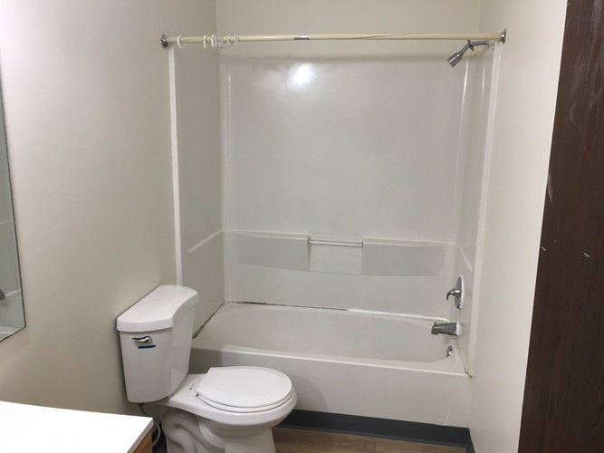 A white toilet sits next to a white bathtub in a small bathroom.