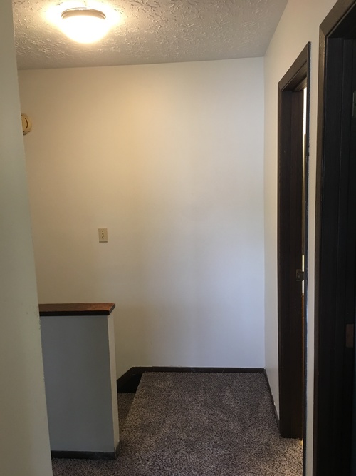 A small room with a grey trashcan and a brown counter.