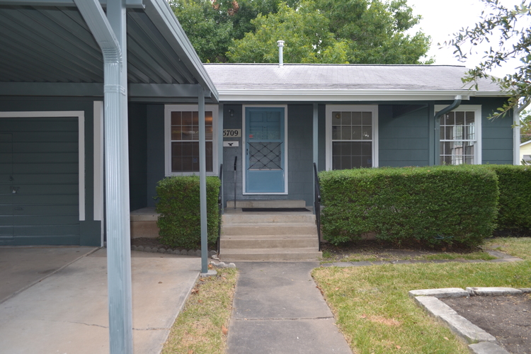 A house with a blue door and a grey roof.